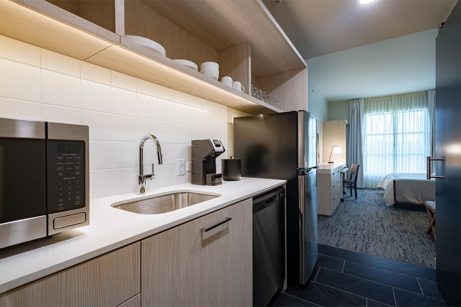 Guest room featuring kitchenette, desk, and ergonomic chair in studio apartment style.